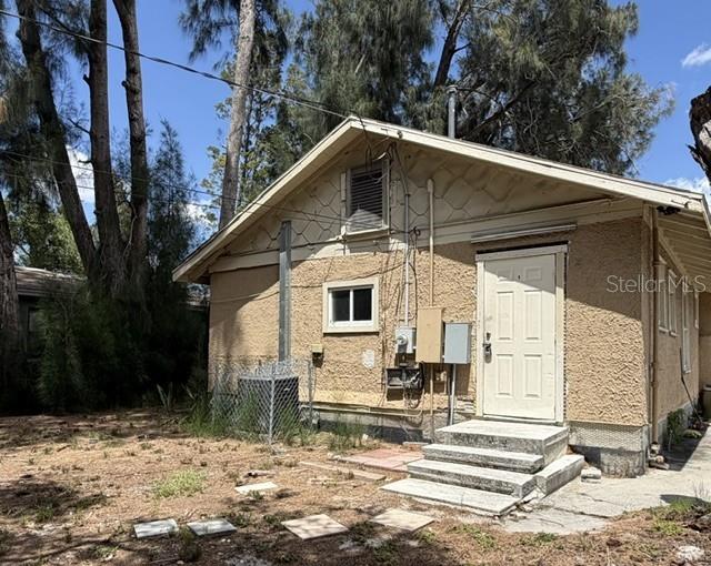 The exterior of a tan stucco house features a white door, concrete steps, and trees — 1727 45TH STREET S UNIT B, ST PETERSBURG, FL