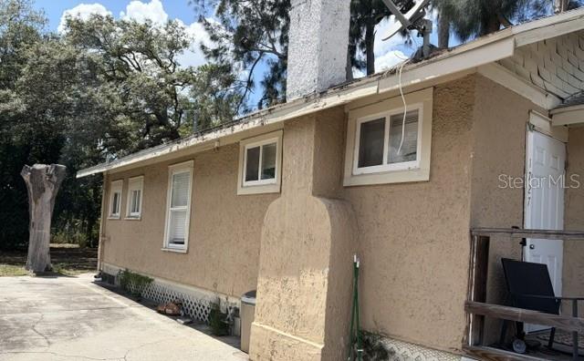 The exterior of a tan stucco house features a chimney, white-framed windows, and a white door — 1727 45TH STREET S UNIT B, ST PETERSBURG, FL