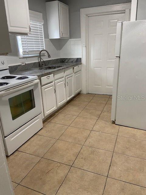 A kitchen features white cabinets, a white stove, a white refrigerator, and tiled flooring — 1727 45TH STREET S UNIT B, ST PETERSBURG, FL