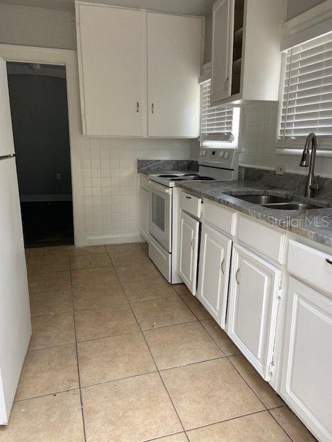 A kitchen features white cabinets, a white stove, a double sink, and tiled flooring — 1727 45TH STREET S UNIT B, ST PETERSBURG, FL