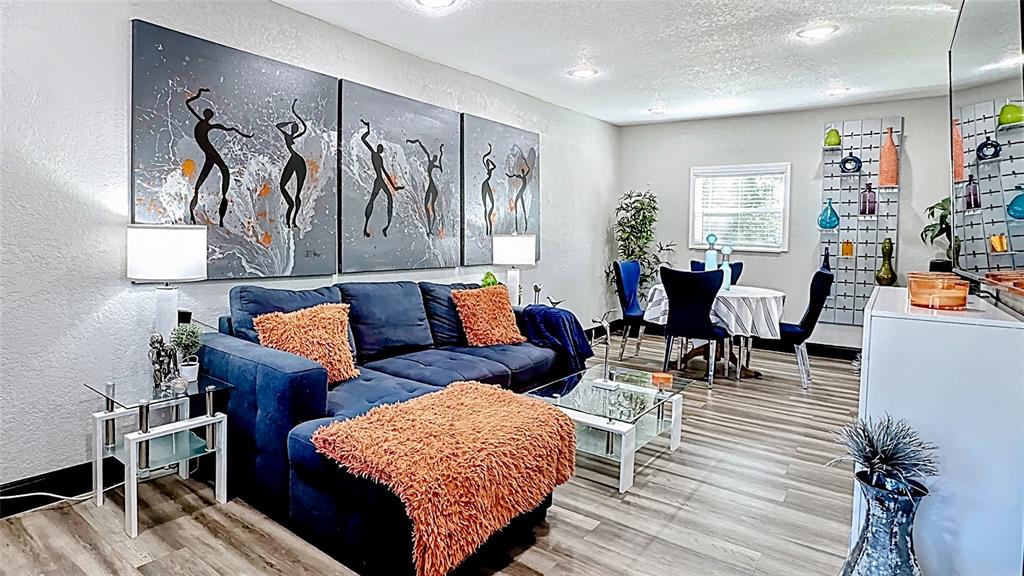 A living room features a blue sectional sofa, orange accents, and large abstract wall art — 1201 W 12TH STREET, SANFORD, FL