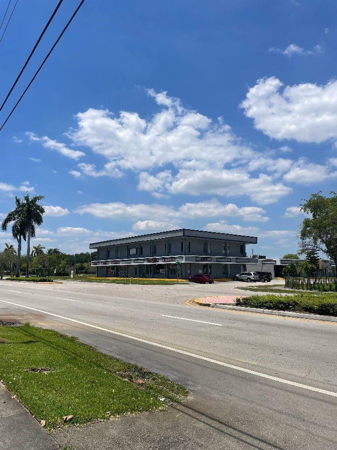 A two-story commercial building with a parking lot sits along a road under a blue sky — 1075 Sunset Strip, Sunrise FL 33313, SUNRISE, FL
