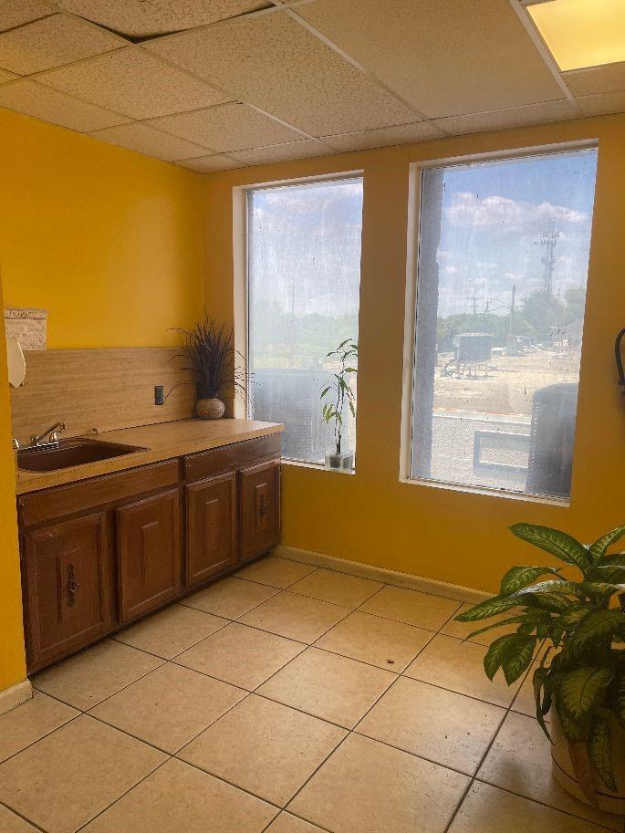 A small room with yellow walls, tile flooring, a wooden sink cabinet, and two large windows — 1075 Sunset Strip, Sunrise FL 33313, SUNRISE, FL