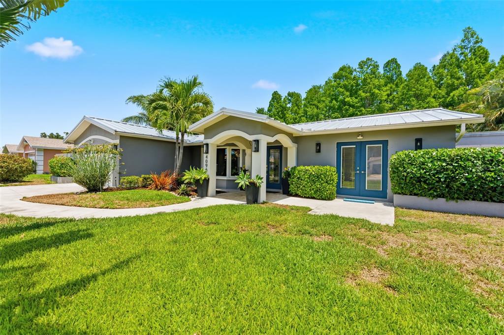 A blue front door with a glass panel and sidelight sits between two potted plants — 4096 38TH STREET S, ST PETERSBURG, FL