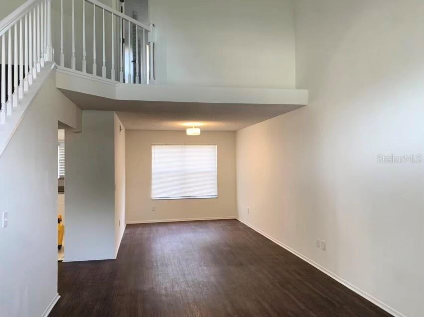 An empty room with dark wood-look flooring, white walls, and an overhead loft area — 5120 MYSTIC POINT COURT, ORLANDO, FL
