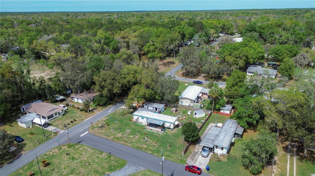 An aerial view shows several mobile homes situated on a wooded lot with paved roads — 7951 E PARTRIDGE LANE, FLORAL CITY, FL