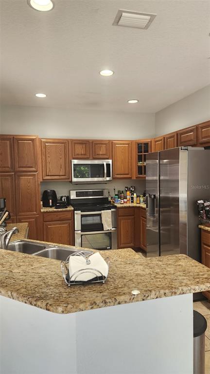 A kitchen features oak cabinets, granite countertops, stainless steel appliances, and recessed ceiling lighting — 13561 HAWK LAKE DRIVE, ORLANDO, FL