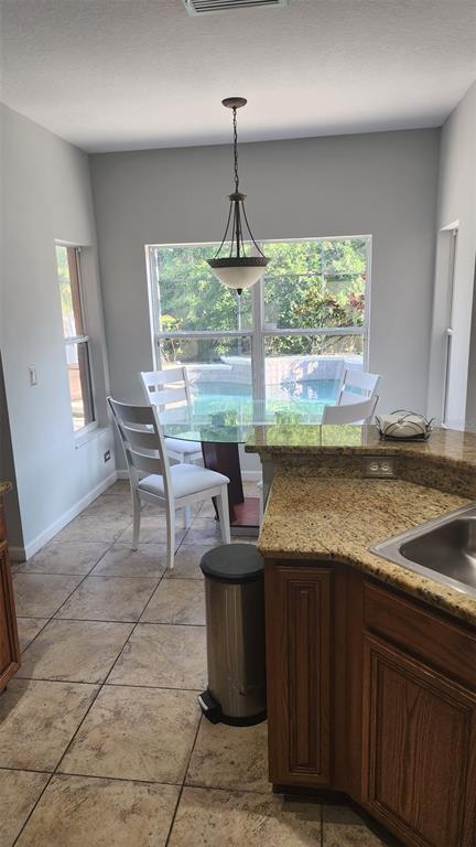 A kitchen dining area features a glass table, white chairs, tile floors, and pool views — 13561 HAWK LAKE DRIVE, ORLANDO, FL