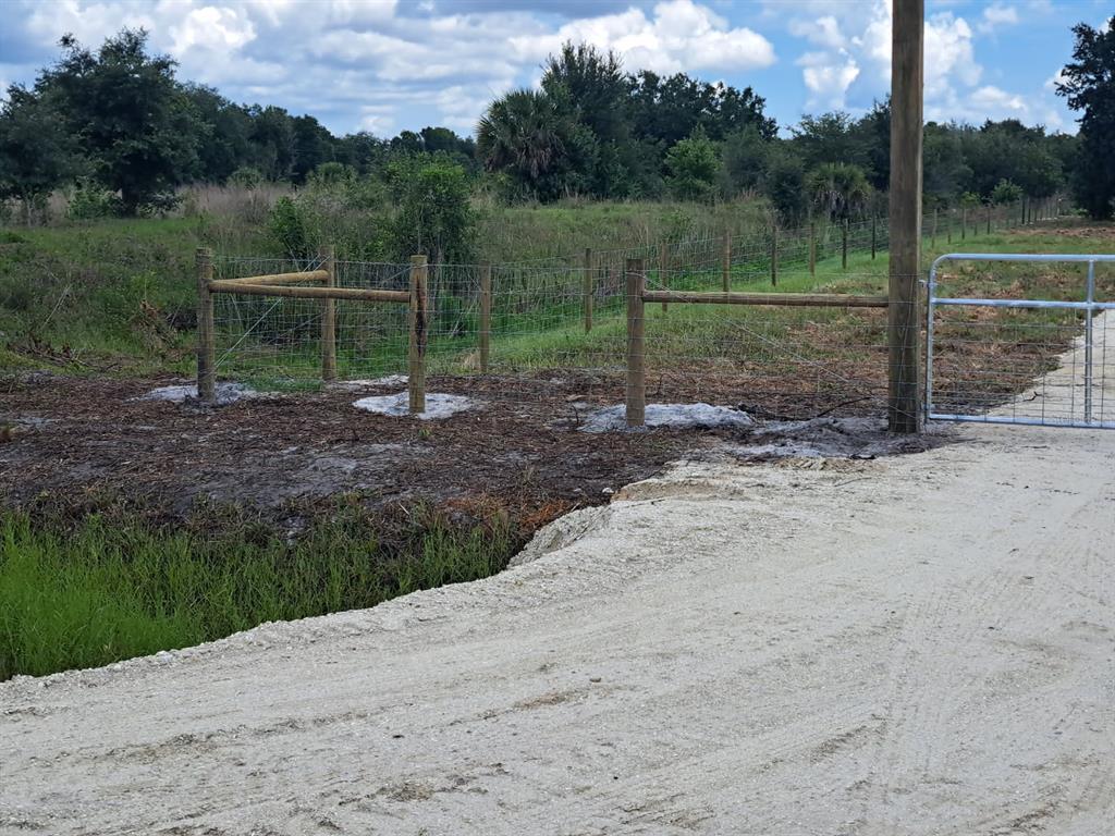 A dirt road leads to a metal gate and a wooden fence in a rural area — 20639 NW 300TH STREET, OKEECHOBEE, FL