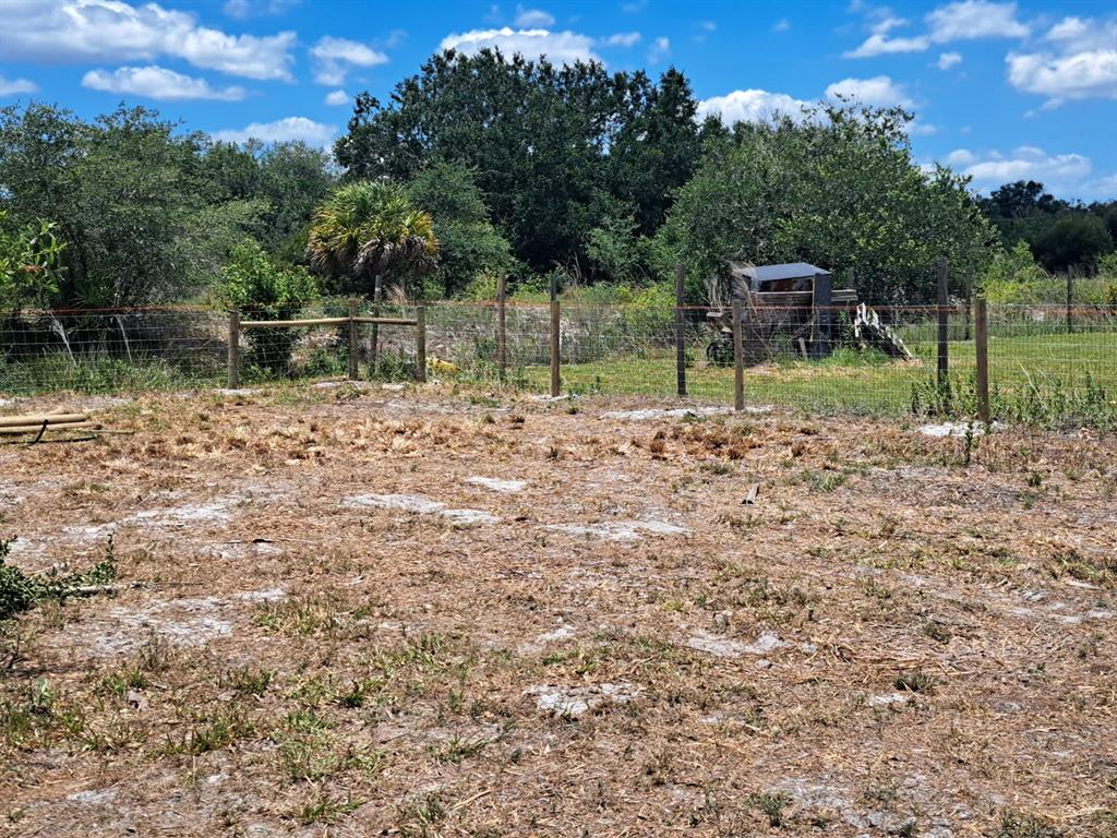 A fenced, dry, and sparsely vegetated plot of land sits before a line of trees — 20639 NW 300TH STREET, OKEECHOBEE, FL