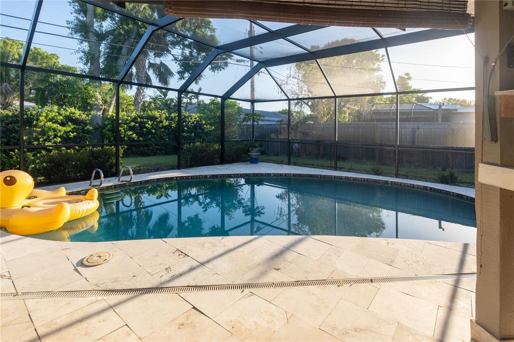 A screened-in patio features a swimming pool, stone pavers, and a yellow inflatable duck — 33 SOUTHWIND DRIVE, BELLEAIR BLUFFS, FL