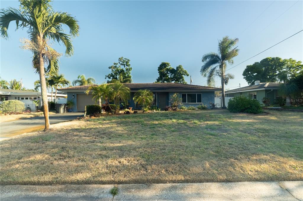 A single-story house with a blue exterior, a two-car garage, and several palm trees — 33 SOUTHWIND DRIVE, BELLEAIR BLUFFS, FL