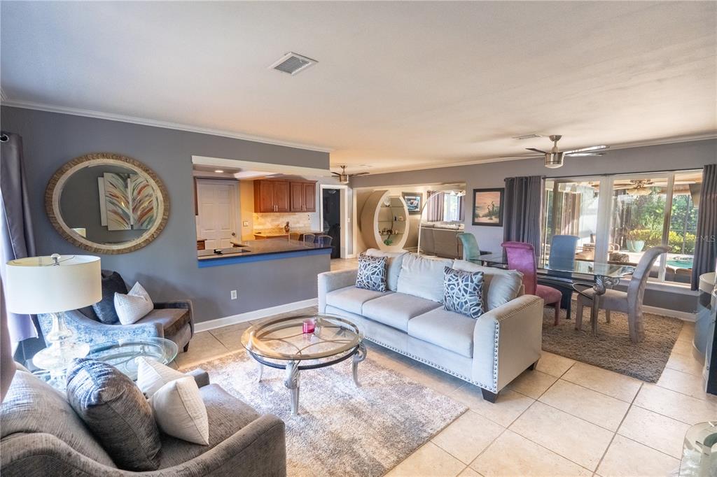 A living room with gray walls, tile flooring, a sofa, and an open kitchen pass-through — 33 SOUTHWIND DRIVE, BELLEAIR BLUFFS, FL