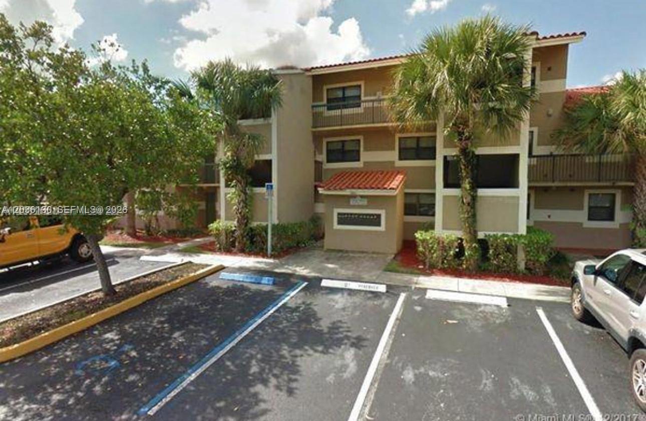 A three-story apartment building with tan stucco walls and a tiled roof — SUNRISE, FL