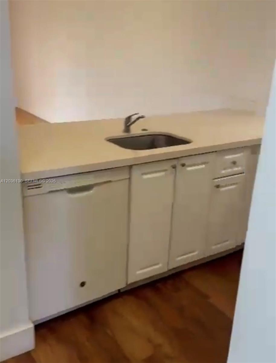 A small kitchen area features white cabinets, a stainless steel sink, and a dishwasher — SUNRISE, FL