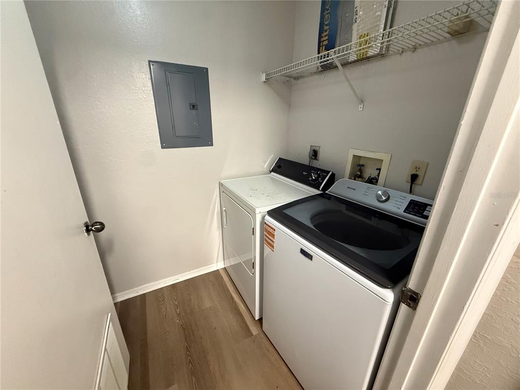 A laundry closet contains a white washer and dryer, a wire shelf, and an electrical panel — 3705 SW 27TH STREET UNIT 1026, GAINESVILLE, FL