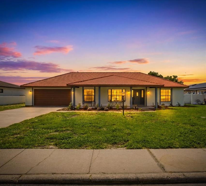 A single-story house with a terracotta tile roof and a front-facing garage at sunset — 2004 LEISURE DRIVE, WINTER HAVEN, FL