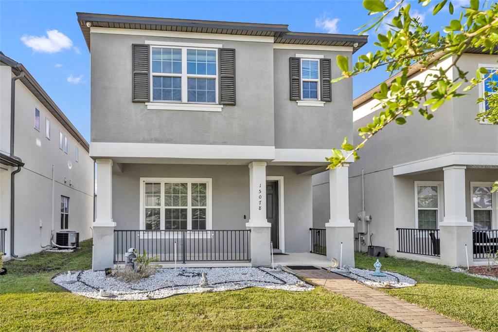A two-story gray house with a front porch, white columns, and a gravel garden bed — 15078 WILLOW ARBOR CIRCLE, ORLANDO, FL