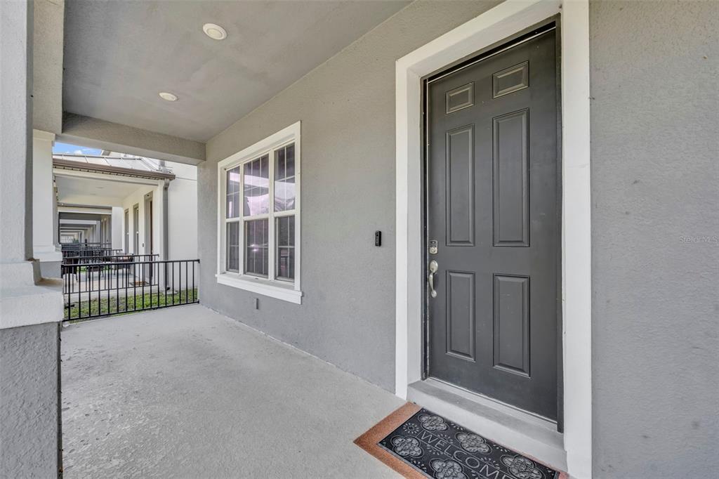 A covered front porch features a gray door, a large window, and a metal railing — 15078 WILLOW ARBOR CIRCLE, ORLANDO, FL