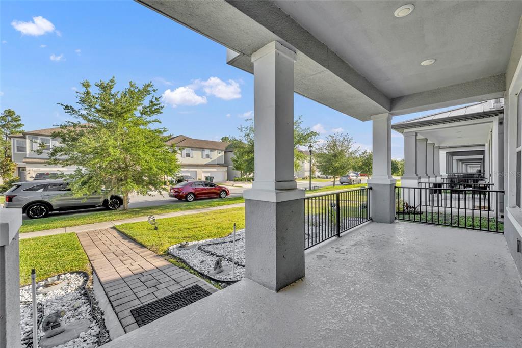 A covered front porch with concrete flooring, metal railings, and a view of the street — 15078 WILLOW ARBOR CIRCLE, ORLANDO, FL