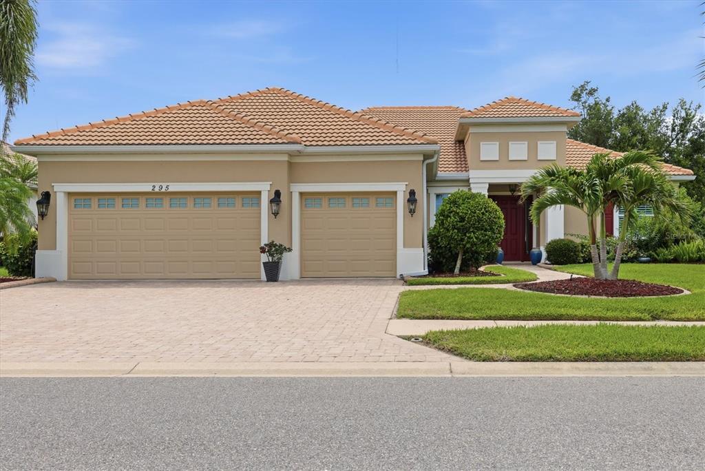 A single-story house with a tan stucco exterior, a tile roof, and a three-car garage — 295 MARSH CREEK ROAD, VENICE, FL