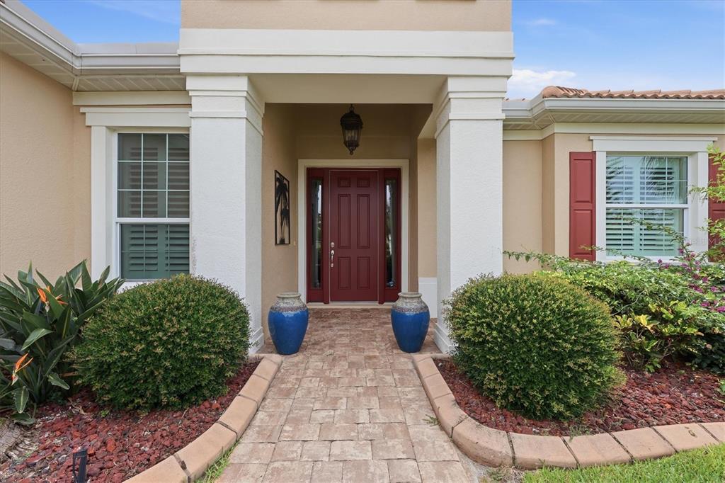 A paved walkway leads to a red front door flanked by two blue decorative urns — 295 MARSH CREEK ROAD, VENICE, FL