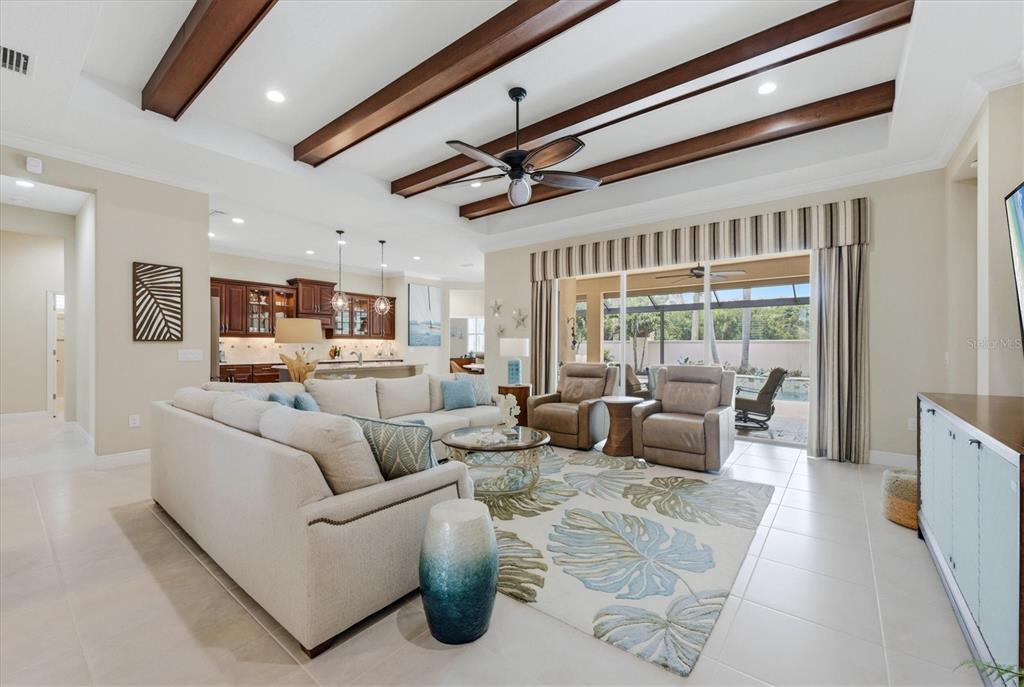 A living room features a tray ceiling with wood beams, tile floors, and sliding glass doors — 295 MARSH CREEK ROAD, VENICE, FL