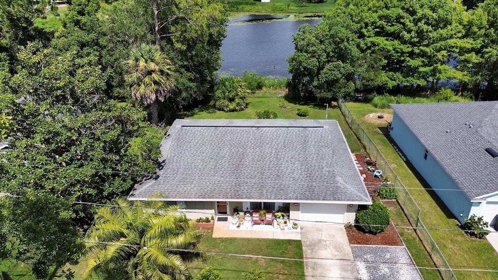 An aerial view shows a single-story house with a gray roof, driveway, and backyard lake — 50 BONITA ROAD, DEBARY, FL