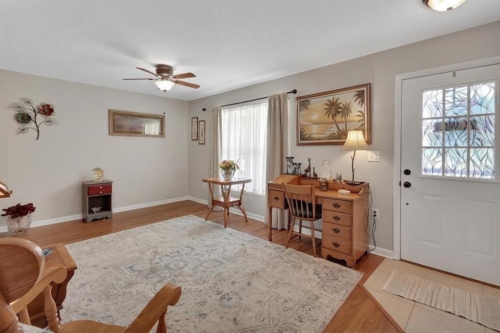 A living room with wood flooring, a ceiling fan, a desk, and a front door — 50 BONITA ROAD, DEBARY, FL