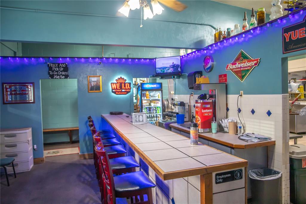 A bar area features a tiled counter, several stools, and various beverage signs on blue walls — 000 RESTAURANT AVENUE, FL