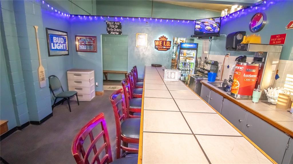 A bar area features a tiled counter, several chairs, and various wall signs — 000 RESTAURANT AVENUE, FL