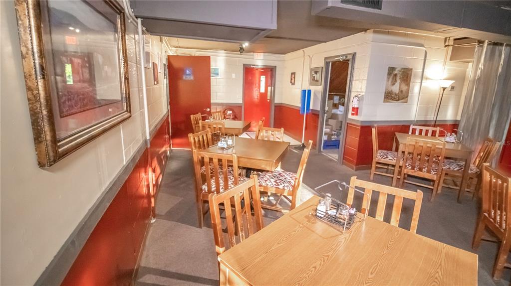 A dining area features several wooden tables and chairs against red and white block walls — 000 RESTAURANT AVENUE, FL