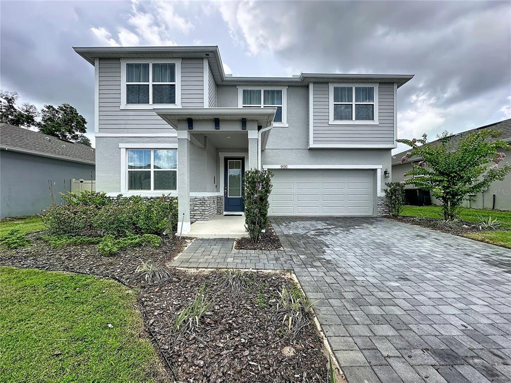 A two-story house with gray siding, a stone-accented entryway, and a paved driveway — 900 HONEY PETAL LANE, DELAND, FL