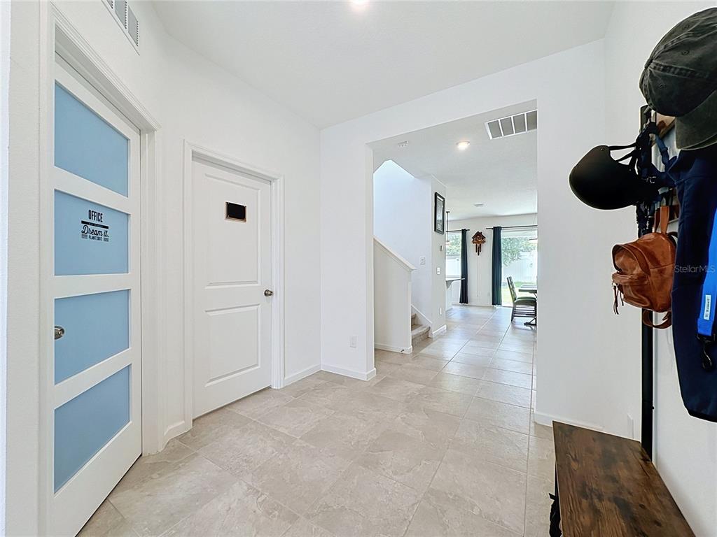 A tiled entryway features a glass-paneled office door, a solid interior door, and a coat rack — 900 HONEY PETAL LANE, DELAND, FL