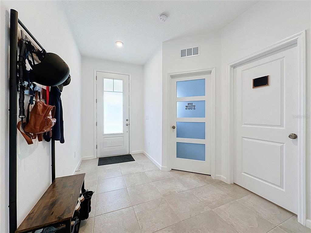 An entryway features tile flooring, a coat rack with a bench, and three white doors — 900 HONEY PETAL LANE, DELAND, FL