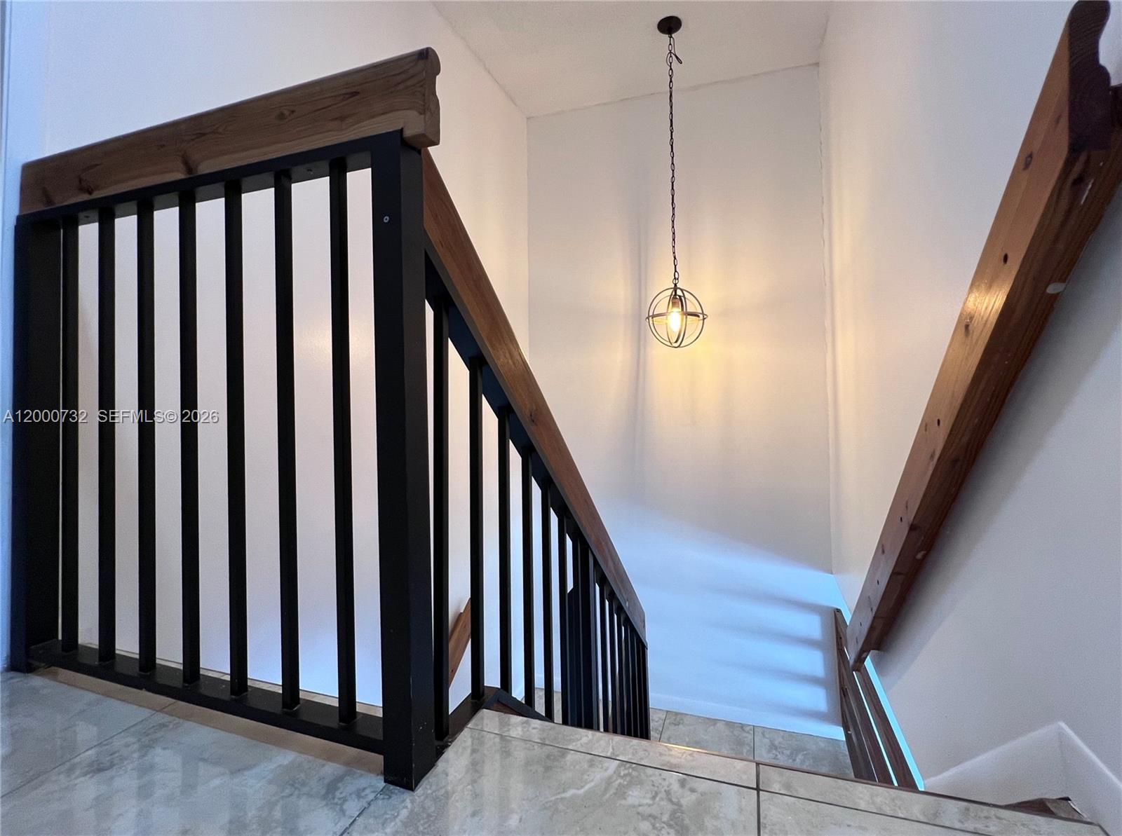 A staircase features black metal railings, wooden handrails, and a hanging orb light fixture — 4530 NW 102nd Ct, Doral FL 33178, DORAL, FL