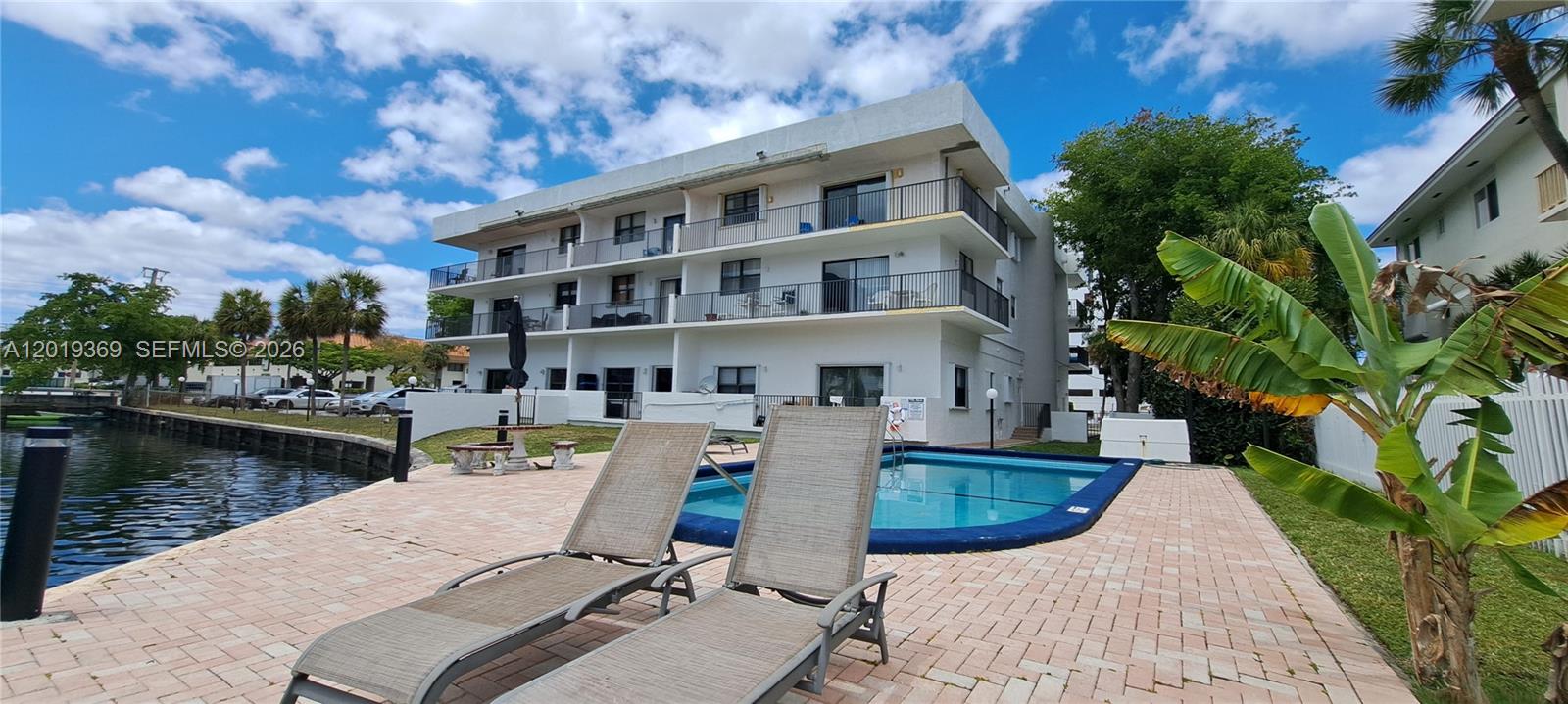 A multi-story apartment building features a swimming pool and lounge chairs on a patio — 1900 Diana Dr # 3E, Hallandale Beach FL 33009, HALLANDALE BEACH, FL