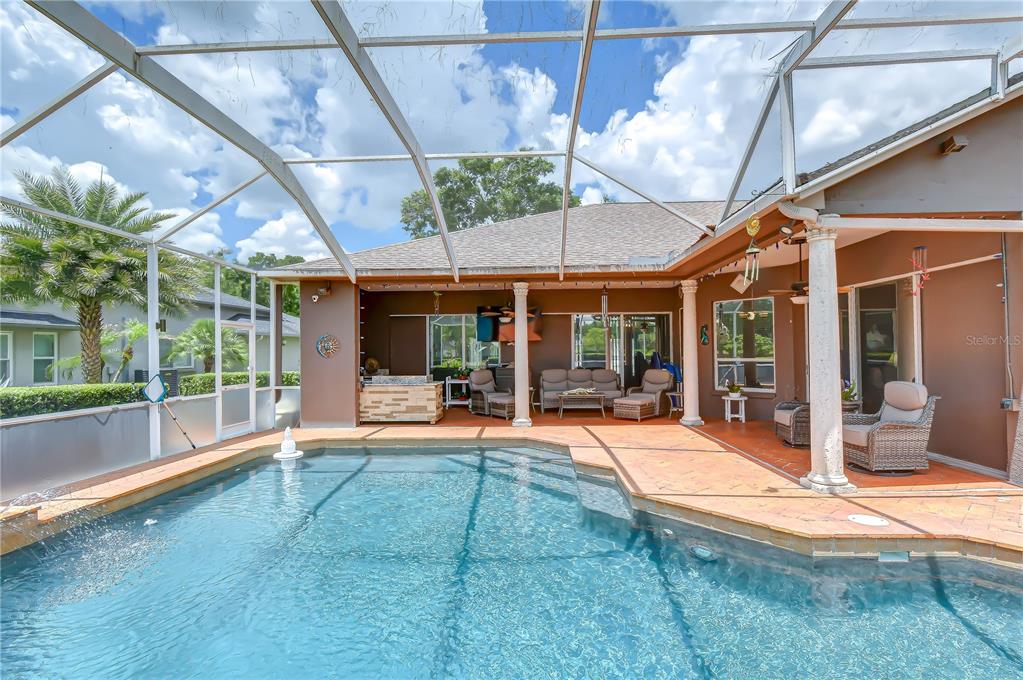 A swimming pool with a screened enclosure sits on a patio next to a house — 3810 TURKEY OAK DRIVE, VALRICO, FL