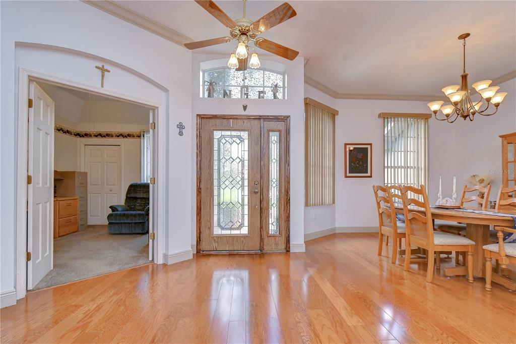 A foyer with hardwood floors leads to a dining area and an adjacent carpeted room — 3810 TURKEY OAK DRIVE, VALRICO, FL
