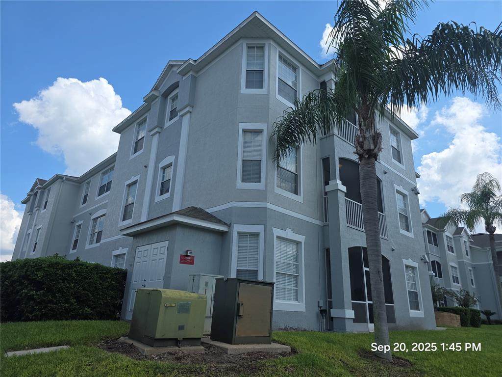 A multi-story apartment building exterior with light gray stucco walls and a palm tree — 2307 SILVER PALM DR UNIT 202, KISSIMMEE, FL