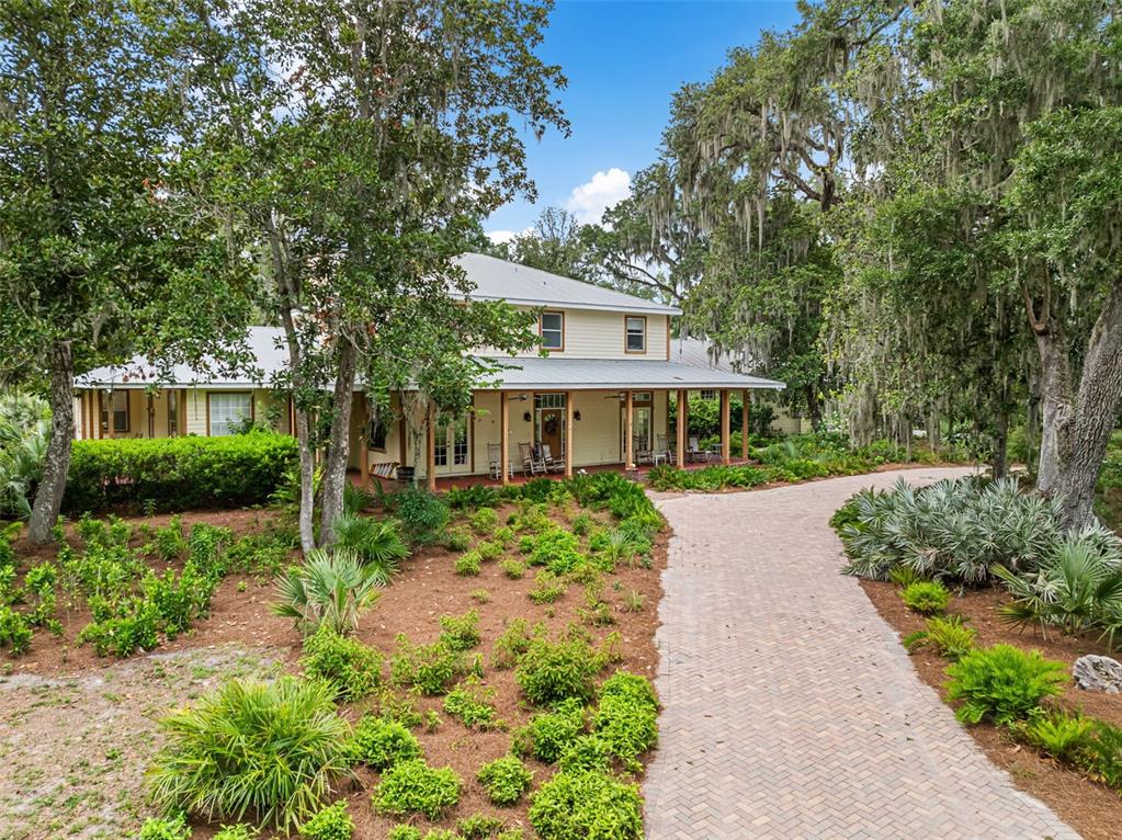 A two-story house with a wrap-around porch and a brick driveway surrounded by trees — 33415 KIEFER ROAD, WESLEY CHAPEL, FL