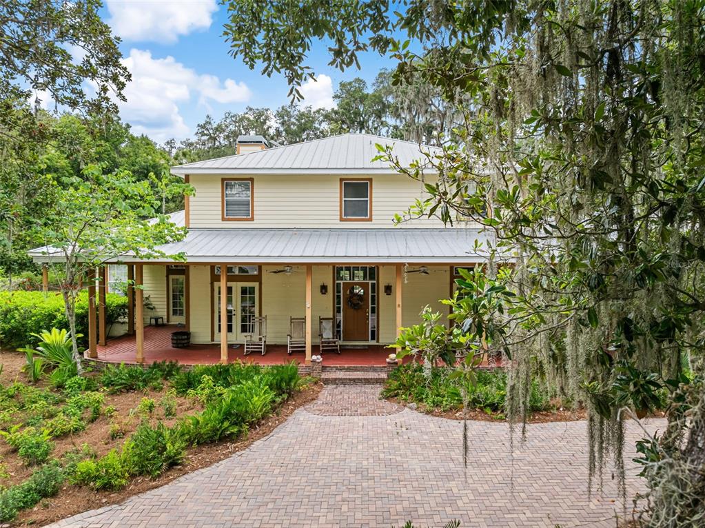 A two-story yellow house with a metal roof and a wide front porch — 33415 KIEFER ROAD, WESLEY CHAPEL, FL