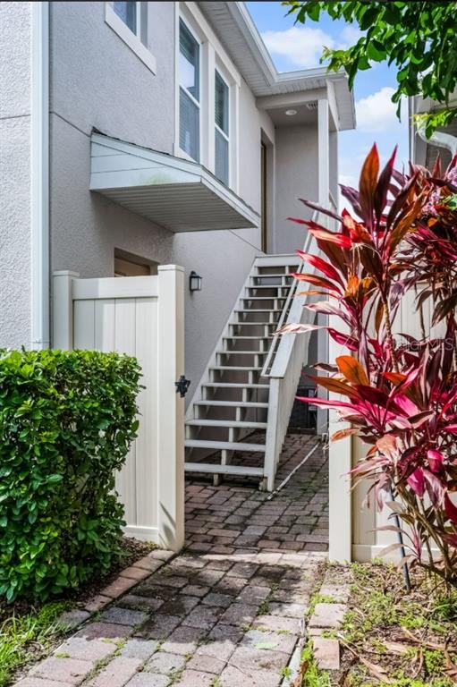 An exterior view shows a white building with an outdoor staircase and a paved walkway — 8623 VIA TRIESTE, WINDERMERE, FL