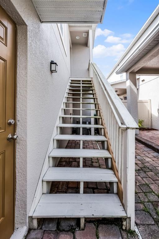 An exterior view of a wooden staircase leading to an upper-level entrance — 8623 VIA TRIESTE, WINDERMERE, FL