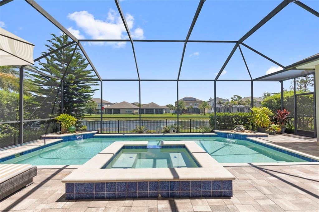 An aerial view shows a suburban house with a pool cage beside a lake — 13340 FAWN LILY DRIVE, RIVERVIEW, FL