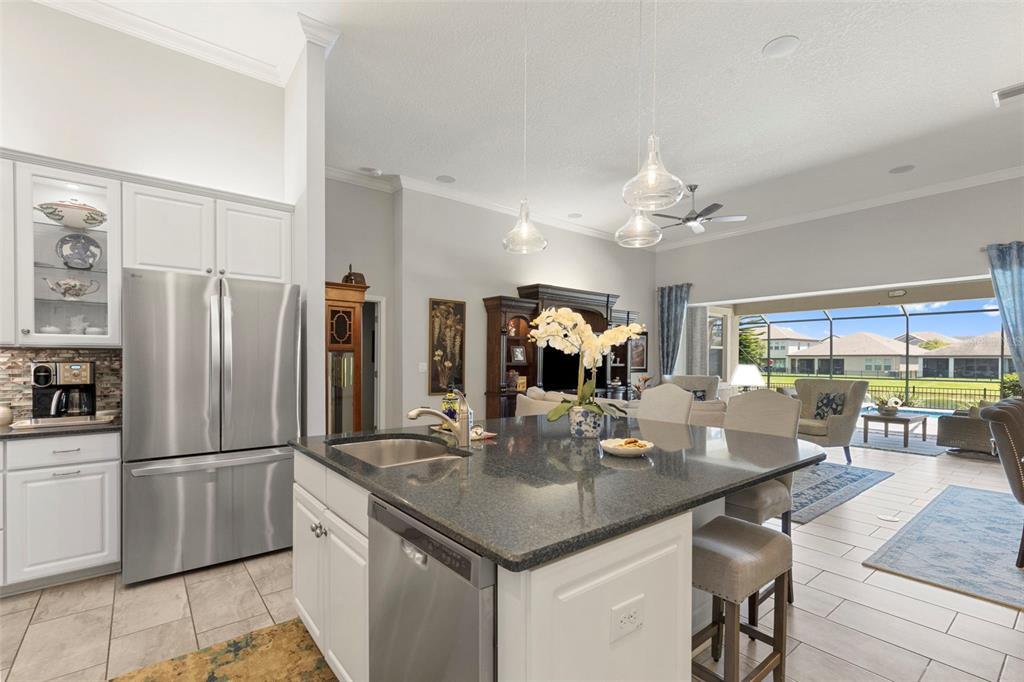 A living room with a large entertainment center, neutral furniture, and a view of a pool — 13340 FAWN LILY DRIVE, RIVERVIEW, FL