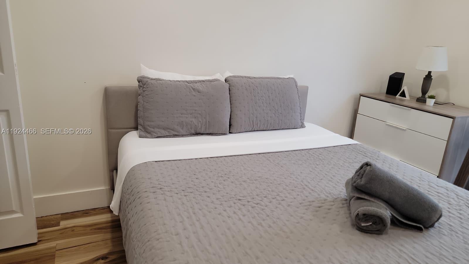 A bedroom features a bed with grey bedding and a white dresser with a lamp — 2820 SW 13th # 4, Miami FL 33145, MIAMI, FL