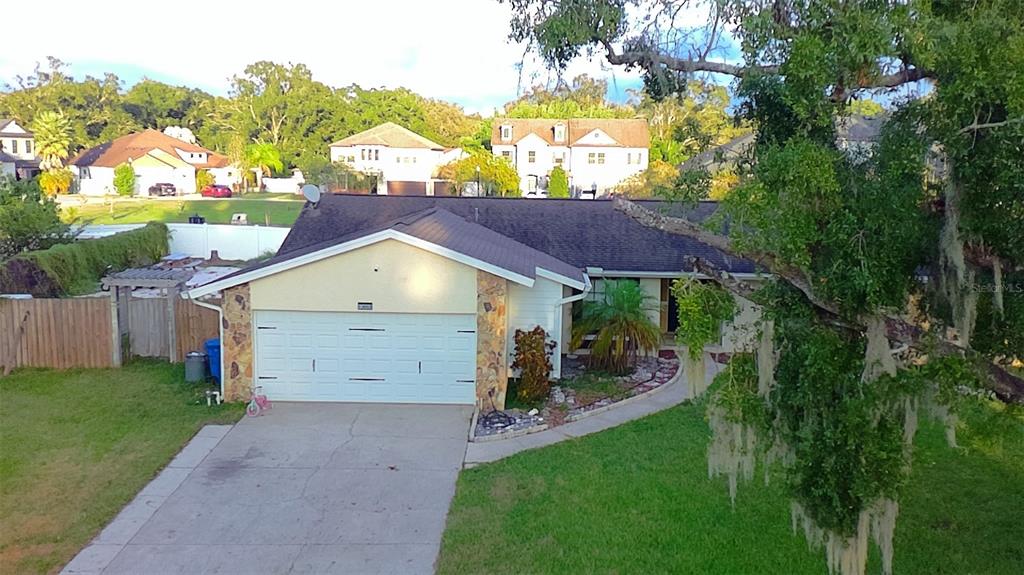 A single-story house with a white garage, stone accents, and a large front lawn — 13603 WESTSHIRE DRIVE, TAMPA, FL