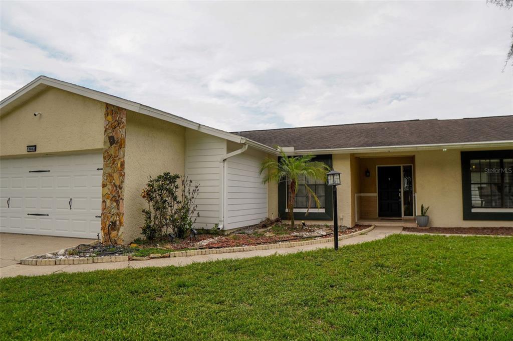 A single-story house with a white garage door, stone accents, and a large front yard — 13603 WESTSHIRE DRIVE, TAMPA, FL