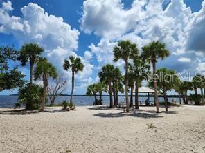 A sandy beach features numerous palm trees and a covered picnic pavilion near the water — 20339 BACHMANN BOULEVARD, PORT CHARLOTTE, FL
